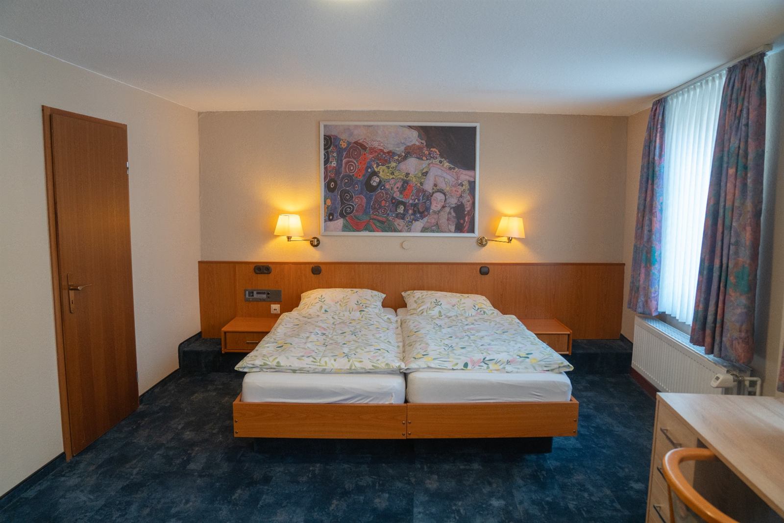 Doppelzimmer mit breitem Bett, zwei Nachttischen und Wandleuchten