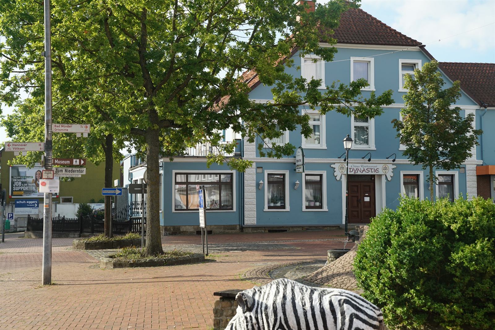 The blue hotel building at Zum Niederntor in Springe, with a large oak tree in front