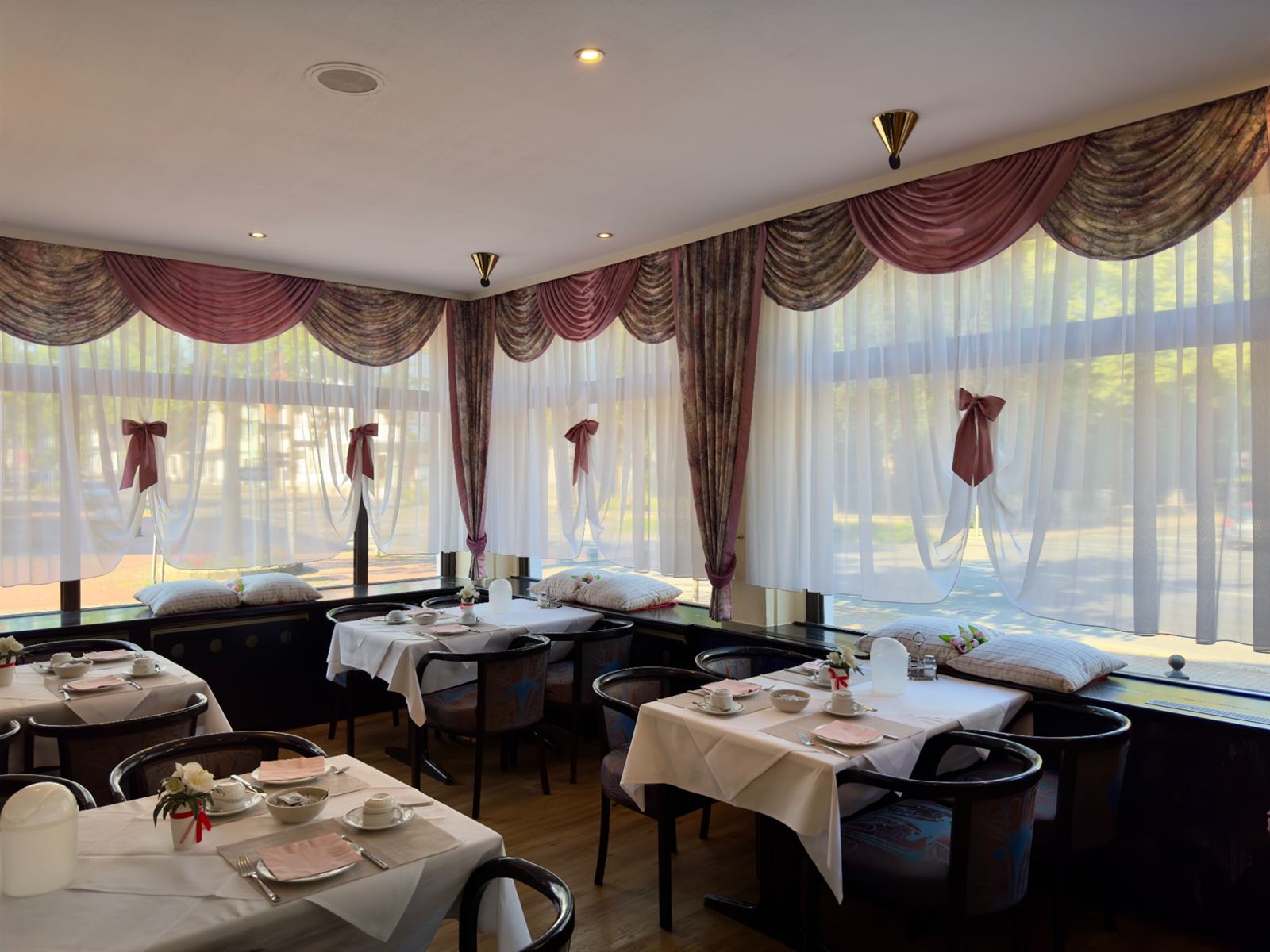 Breakfast room with white table settings and large windows overlooking the square
